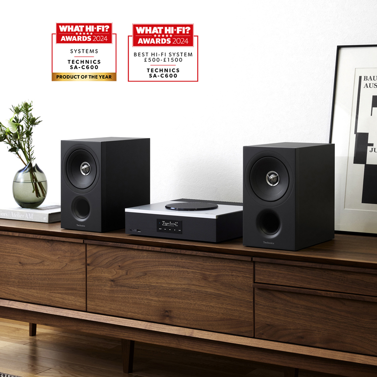 A pair of black speakers and a central unit placed on a wooden cabinet. 