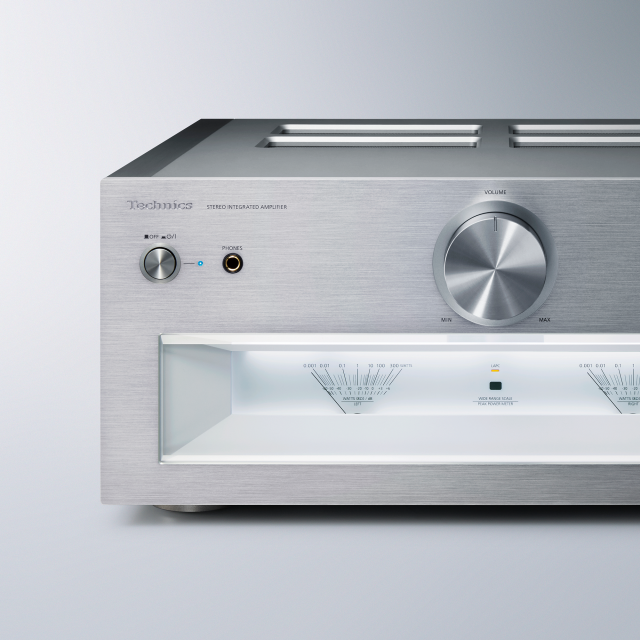 Gros plan d'un amplificateur, ou récepteur audio, argenté, montrant un gros bouton de volume et plusieurs boutons.