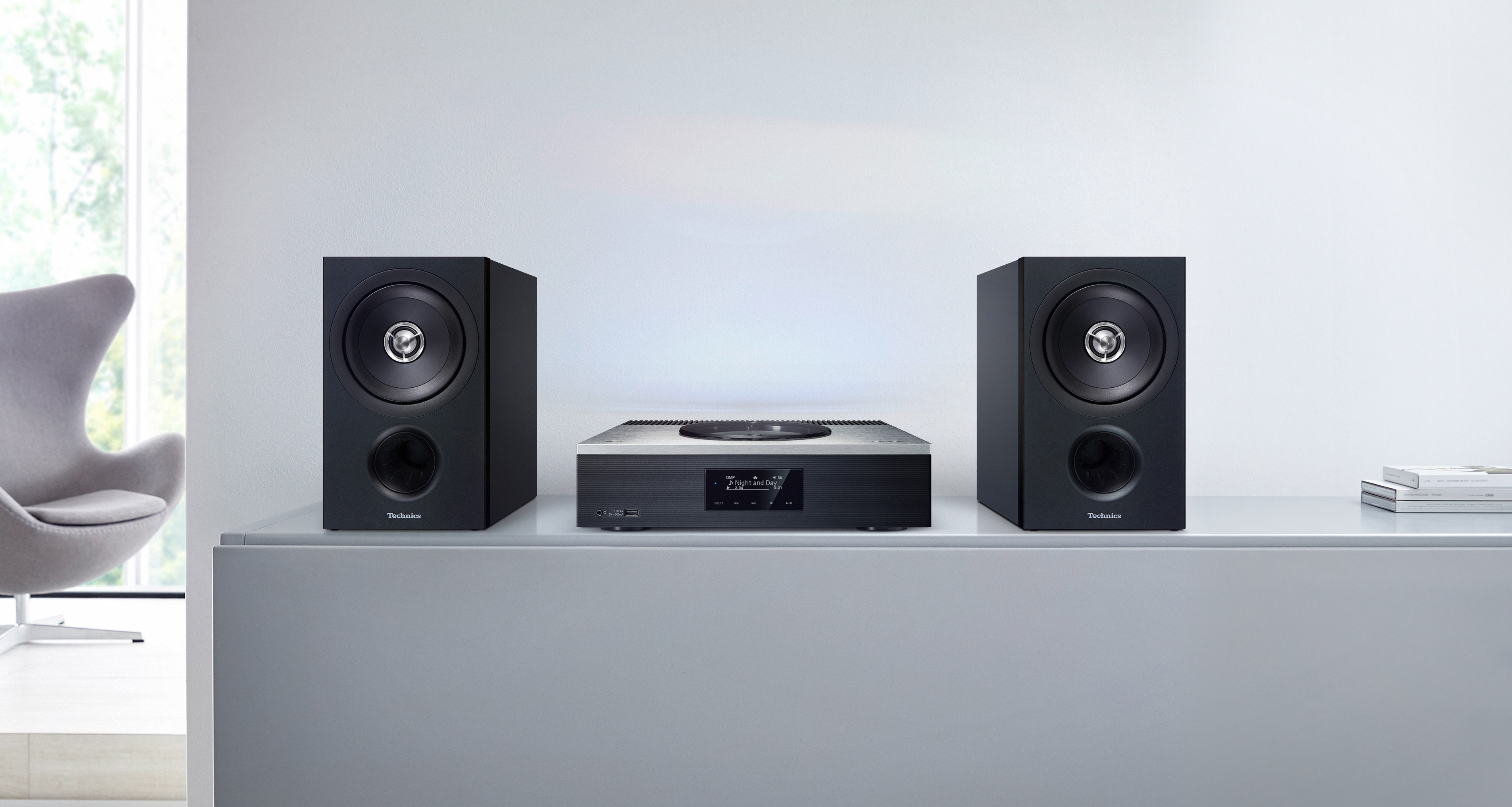 Der Technics SA-C600 CD-Netzwerk-Receiver steht zusammen mit zwei SB-C600 Regallautsprechern auf einem Sideboard.