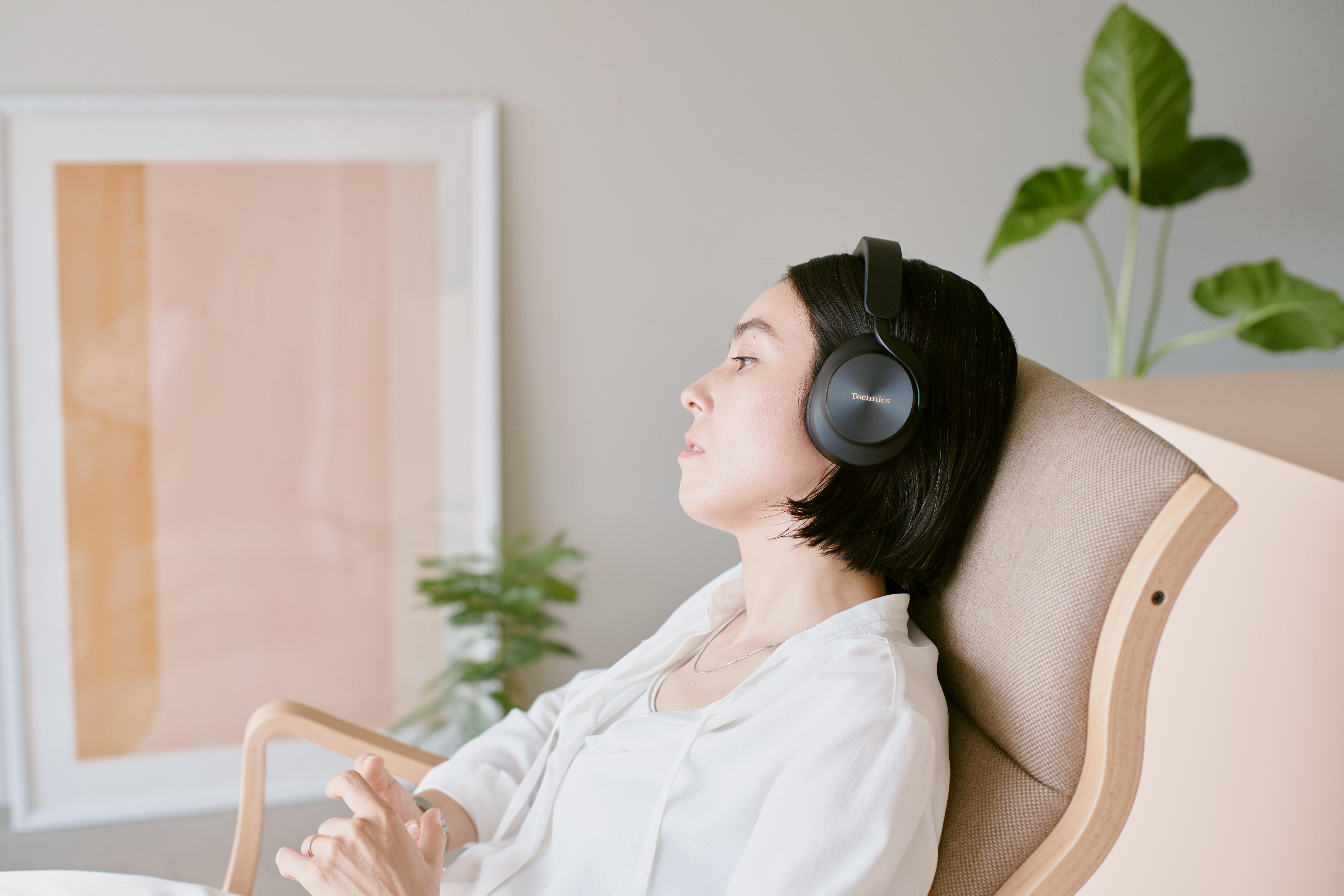 Una donna si rilassa a casa indossando cuffie Technics nere circumaurali.