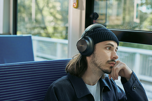 Un uomo indossa cuffie Technics circumaurali mentre viaggia in treno.