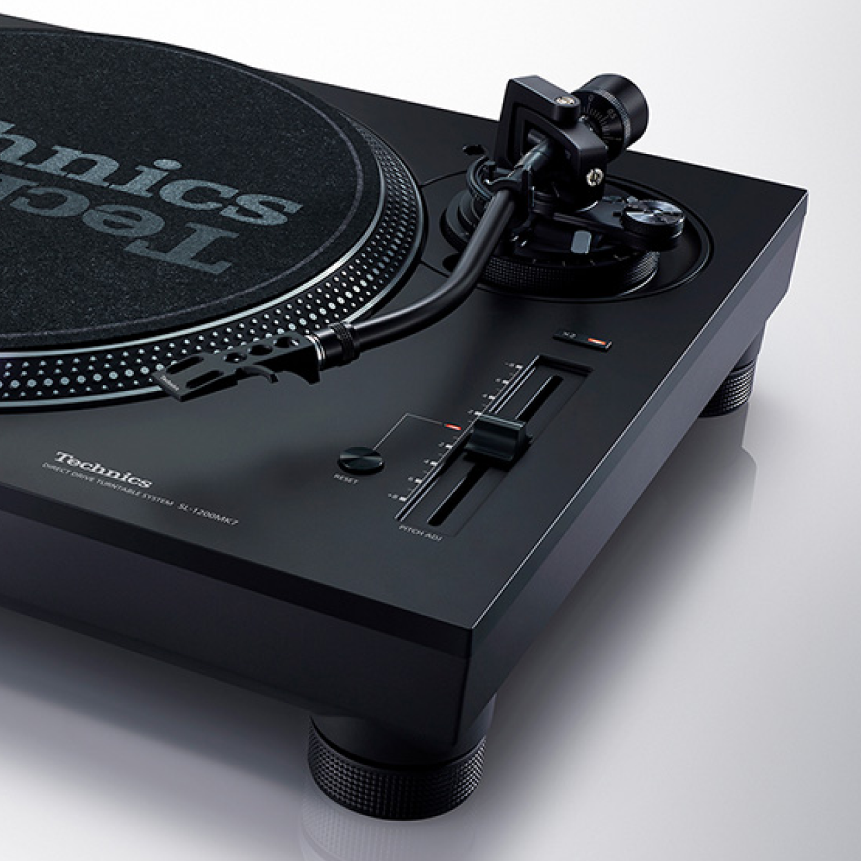 This image shows a three-quarter view of a Technics turntable, featuring an S-shaped tonearm positioned over the platter, a vertical pitch control fader, and control buttons on a matte black deck.