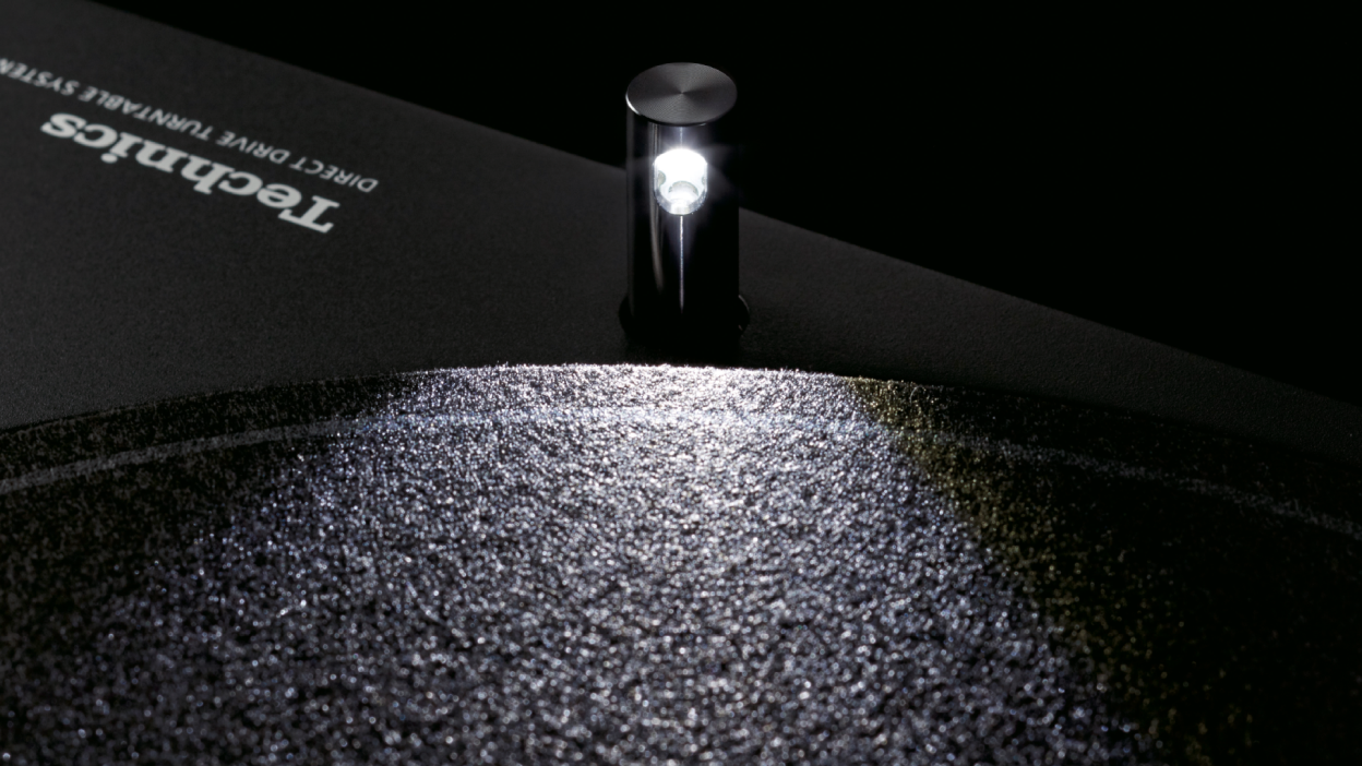 This image shows a close-up of a pop-up stylus illuminator casting light onto a turntable platter, highlighting the textured surface in a dark setting for improved stylus visibility.