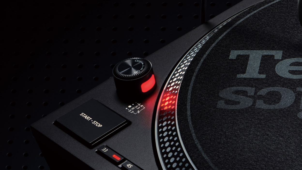 This image shows a close-up of a turntable’s start/stop button, speed selector, and strobe light illuminating the rotating dot pattern along the edge of the platter.