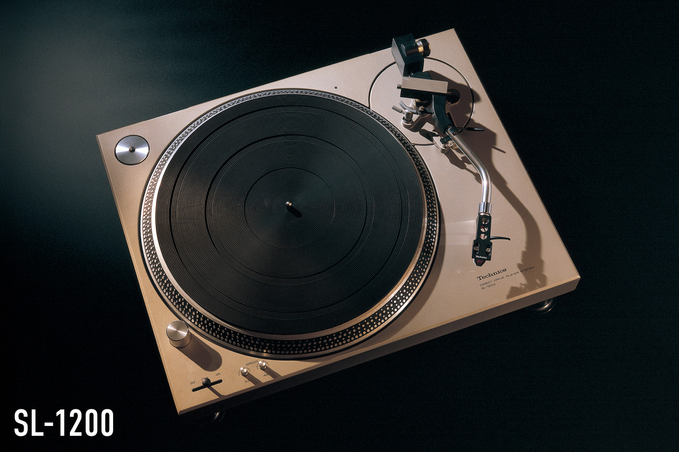 Photograph of the Technics SL-1200 turntable in gold finish, shot from above against a dark background, with the model name "SL-1200" displayed in the lower left.