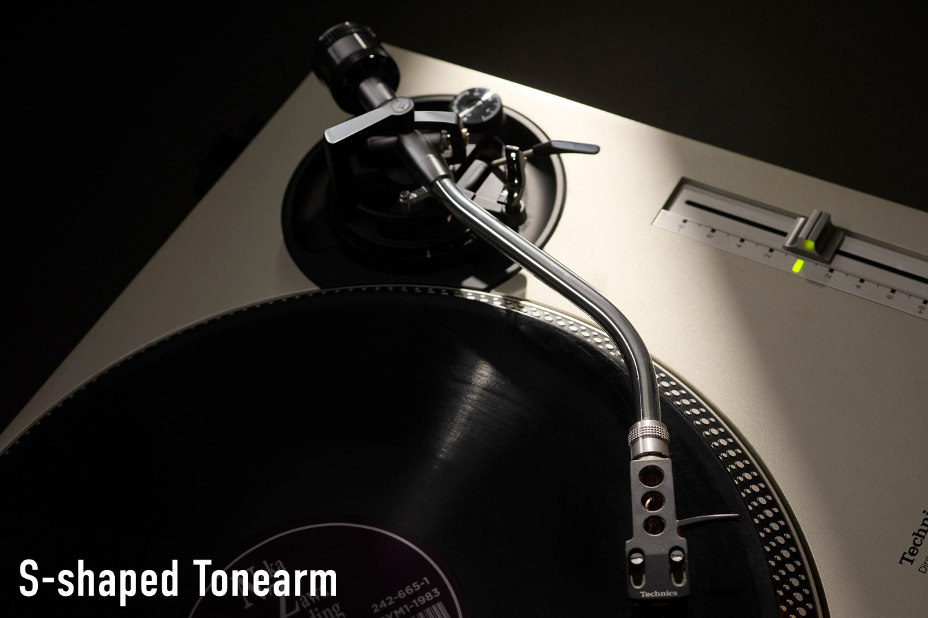 Close-up photograph of the S-shaped tonearm on a Technics turntable with a vinyl record visible, with the label "S-shaped Tonearm" in white text at the bottom left.