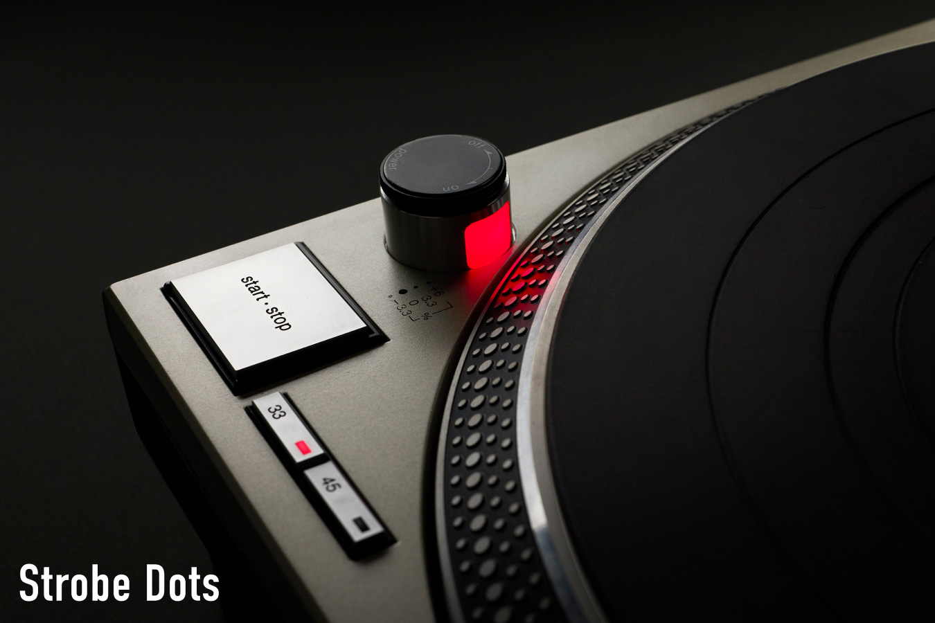 Close-up photograph of the start/stop button and red-illuminated strobe dots on a Technics turntable, with the label "Strobe Dots" in white text at the bottom left.