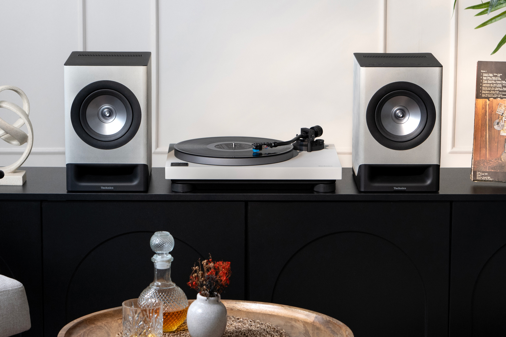 Les enceintes sans fil CX700 et la platine 40CBT de Technics s’intègrent avec élégance sur un meuble en bois, au cœur d’un salon à la décoration soignée. Les deux produits arborent une élégante finition Gris satin.
