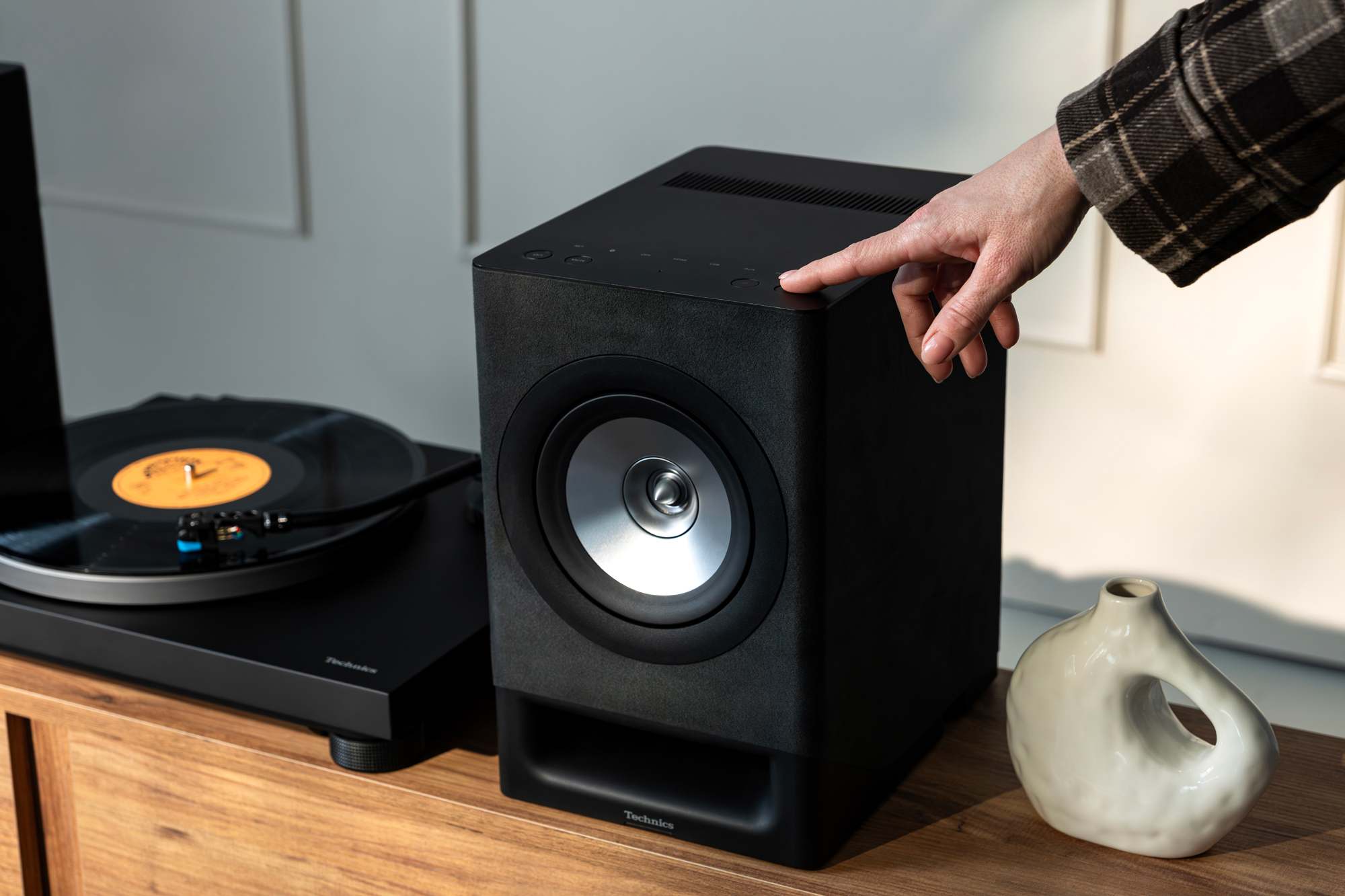 Gros plan sur les enceintes sans fil Technics CX700 et la platine Technics 40CBT. Les deux produits sont présentés en finition Gris satin, dans un salon contemporain au design soigné.