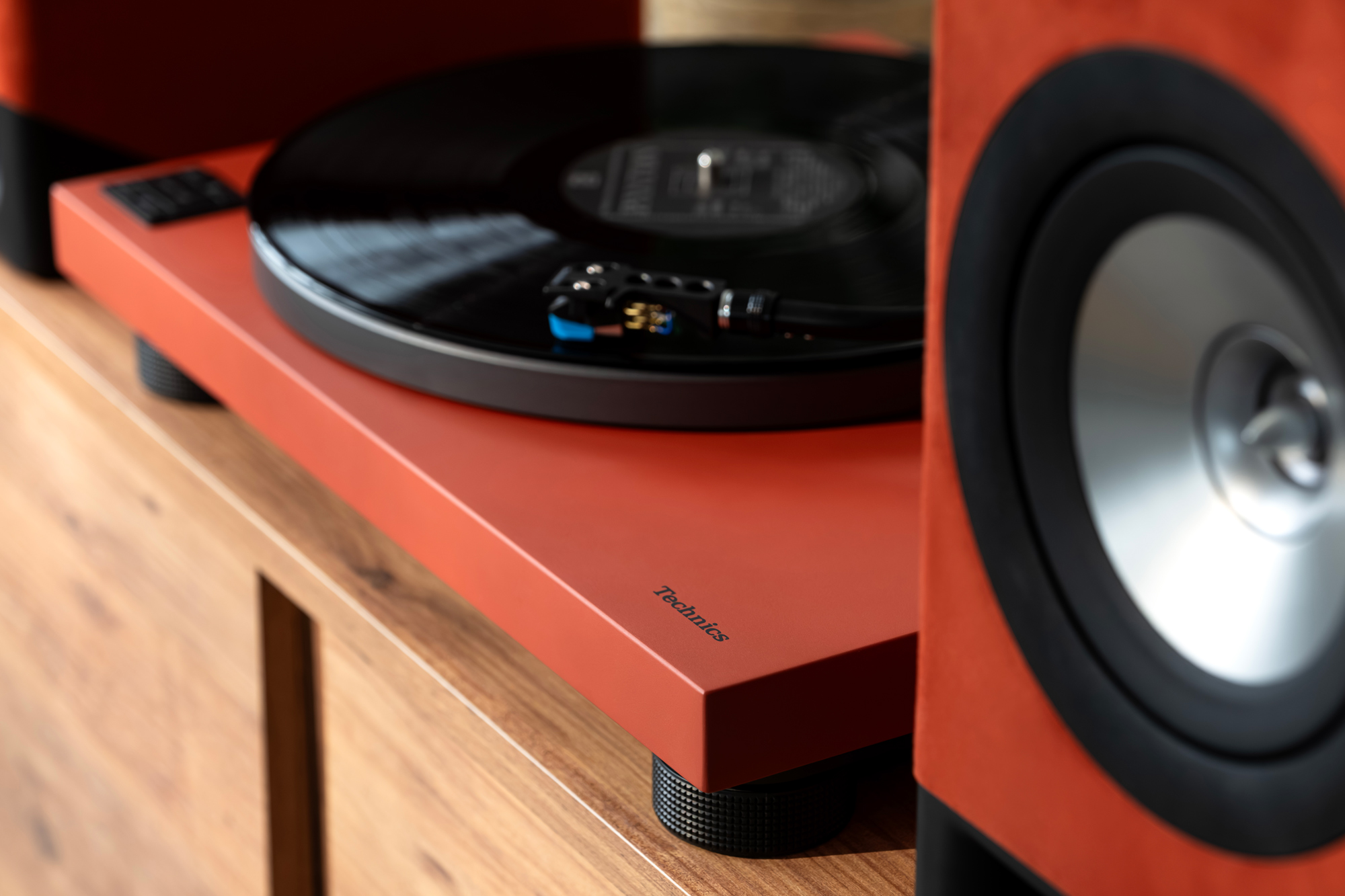 Gros plan sur les enceintes sans fil Technics CX700 et la platine Technics 40CBT. Les deux produits sont présentés en finition Terracotta Brown, dans un salon contemporain au design soigné.